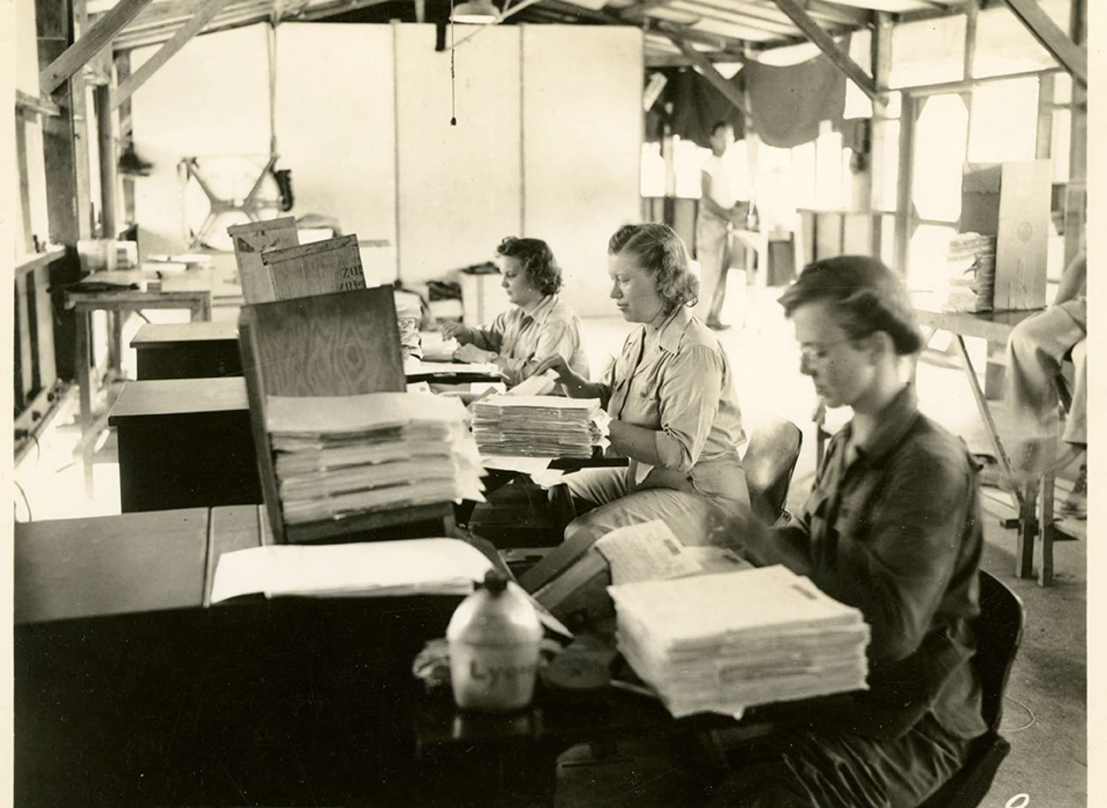 Women handling stacks of letters at Recordak microfilm machines in a V-Mail station in Port Moresby in 1944.