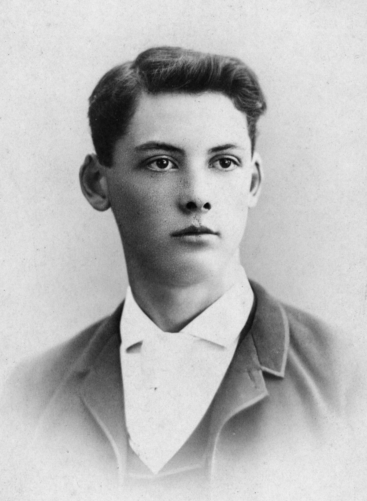 Black-and-white studio portrait of the young Edwin Arlington Robinson in a dark jacket and white collar, with swept-back hair and his face turned slightly to one side.