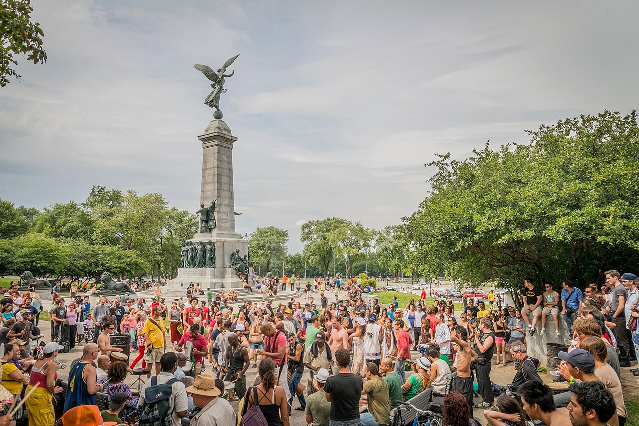 Drummers and listeners form a circle below the tall Cartier monument, crowned by a winged figure, in Montréal’s Mount Royal Park.