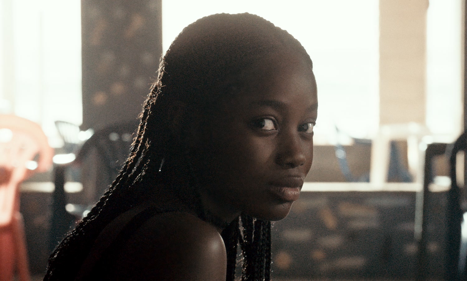 Ada, played by Mama Sané, looks sideways in a warmly backlit still from Atlantics.