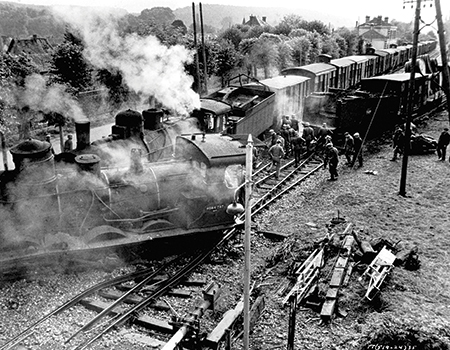 Steam locomotives, wagons, smoke, and people fill the tracks in a black-and-white photograph from The Train.