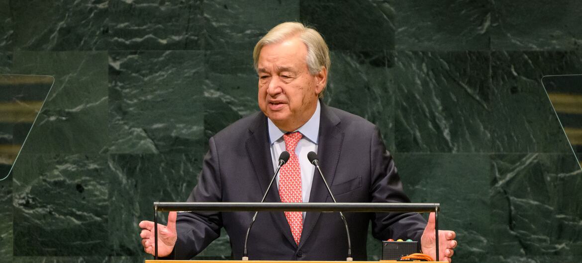 António Guterres speaks at the UN General Assembly podium against its green marble backdrop.