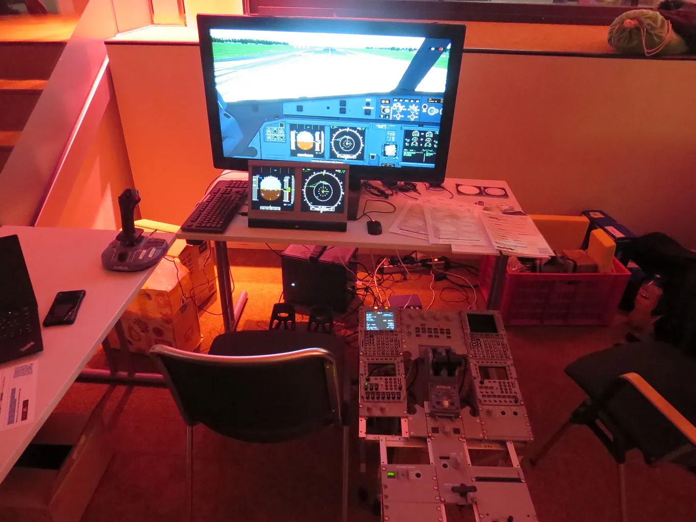 A homemade Airbus flight-simulator cockpit at 39C3, with a central monitor, two flight displays, a sidestick, and a 3D-printed pedestal covered in controls.