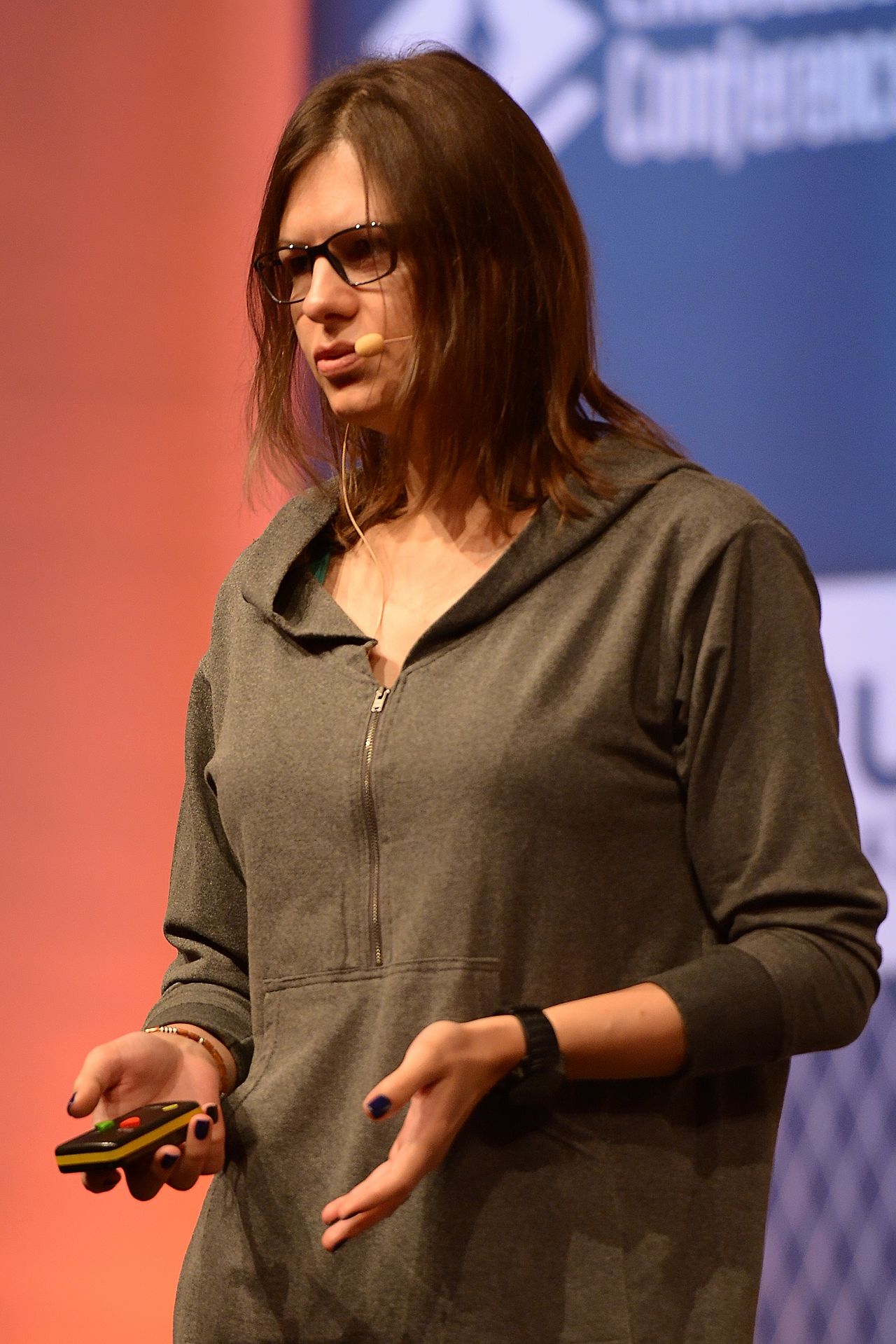 Joanna Rutkowska speaks onstage at LinuxCon Europe 2014, wearing a headset microphone and holding a presentation remote.