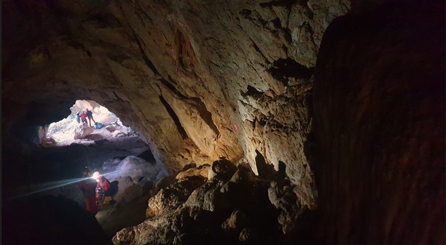Helmeted cavers with headlamps among the rocks of a cave during a digital surveying workshop.