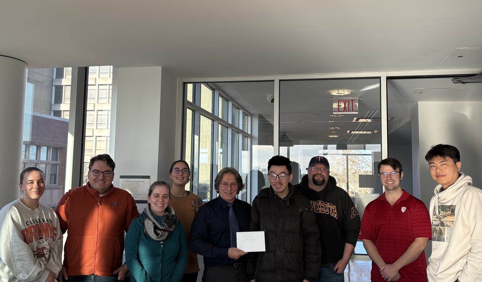 Nine people pose together in a university room following Jinzhe Zeng’s doctoral thesis defense.