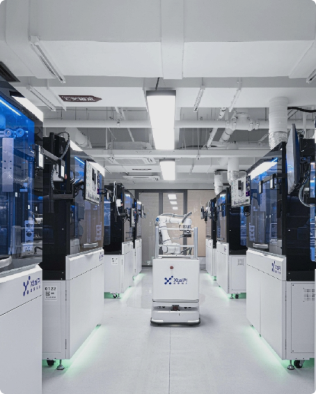 Rows of enclosed XtalPi laboratory workstations flank an aisle with a mobile laboratory robot.