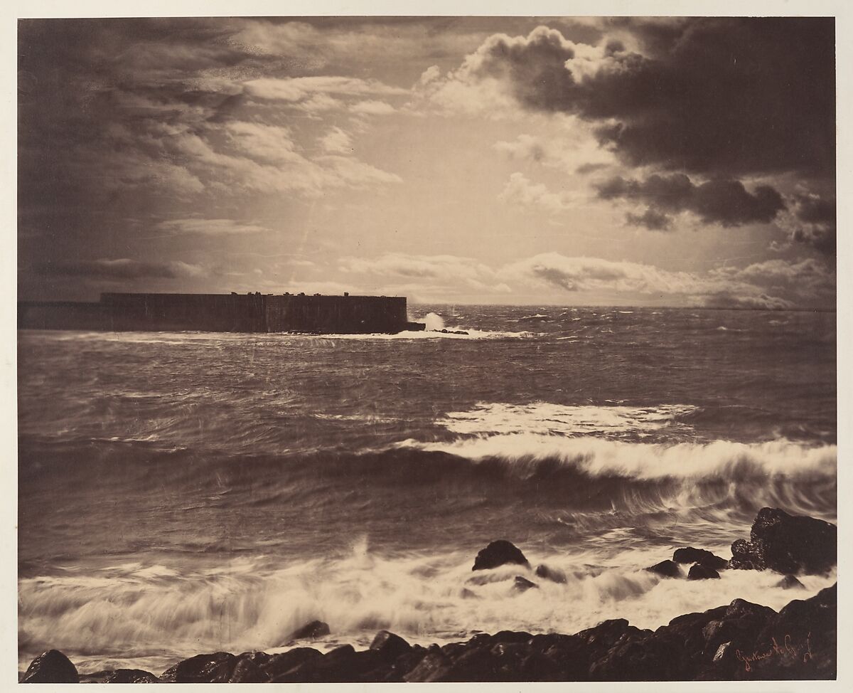 Gustave Le Gray’s sepia photograph of foaming waves, dark foreground rocks, a distant breakwater extending from the left, and a broad clouded sky.