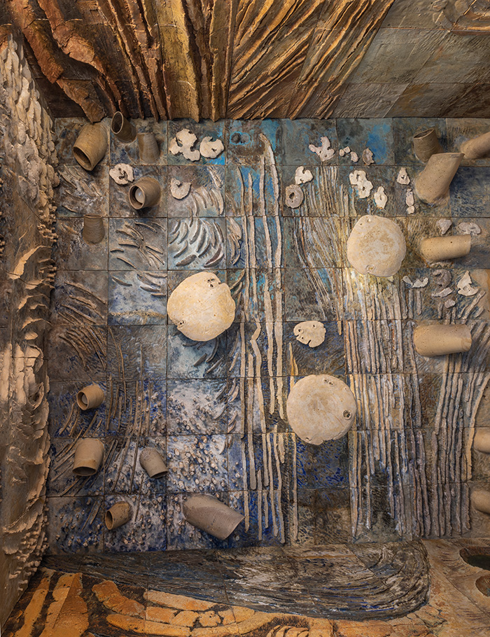 Detail of Earth, Water, Sky: blue and brown grooved ceramic tiles, pale projecting disks, and hollow tubular forms.