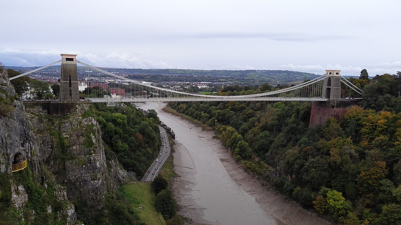 Clifton Suspension Bridge spanning the wooded Avon Gorge, with its stone towers and suspended roadway visible.