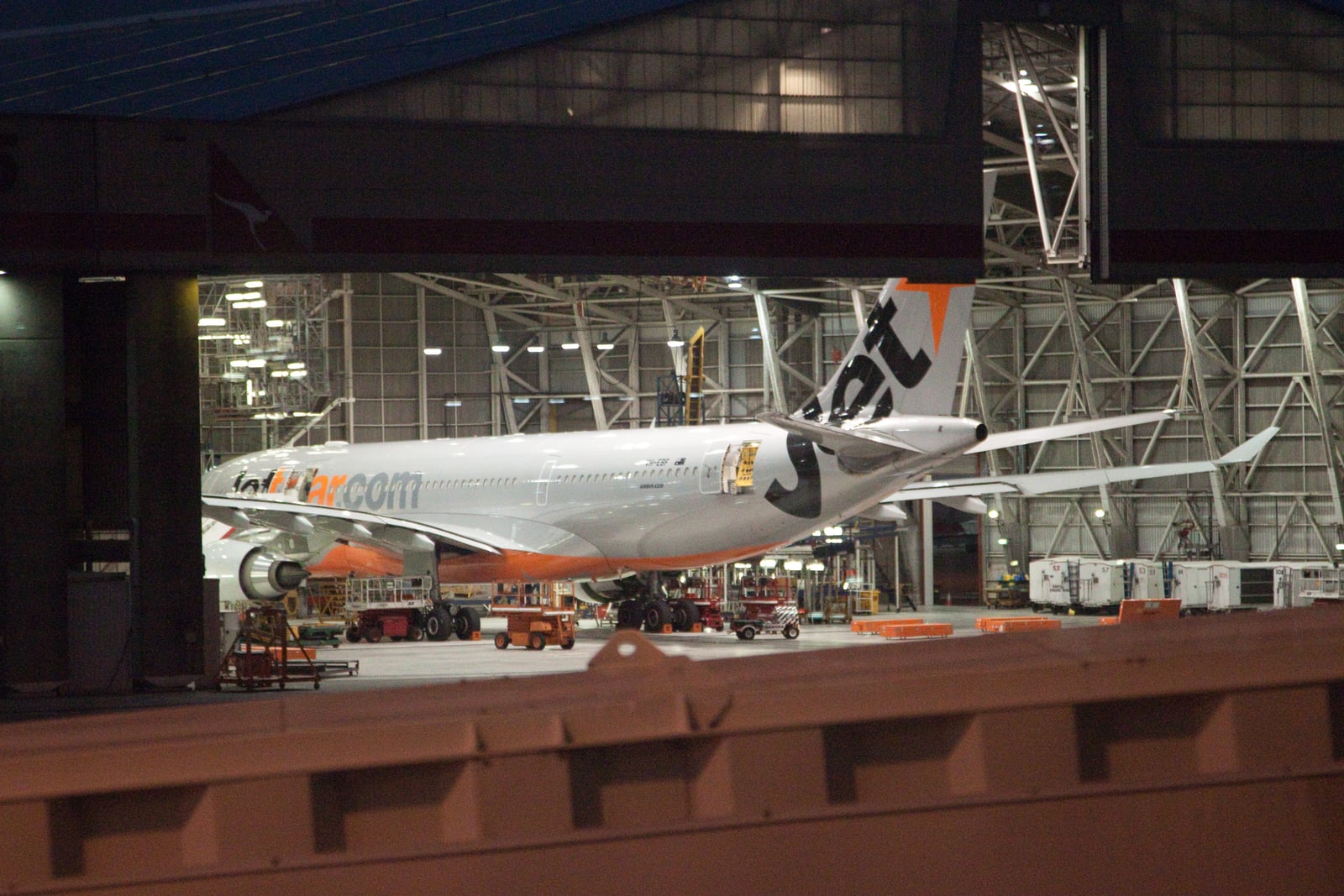 A Jetstar Airbus A330 inside a brightly lit maintenance hangar at Sydney Airport.