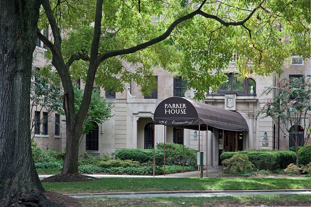 A tree shades the entrance canopy and pale stone facade of Parker House apartments on Connecticut Avenue in Washington, D.C.