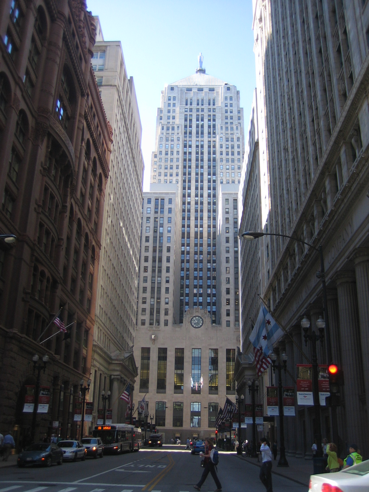The Chicago Board of Trade Building's stepped tower rises between neighboring buildings in daylight.