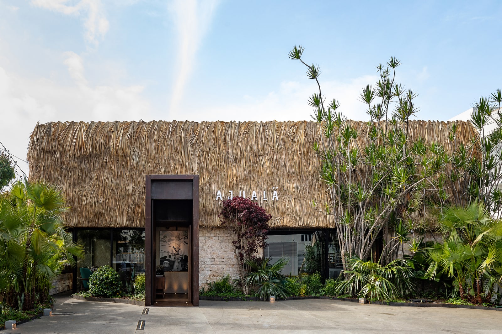 Ajualä's plant-fiber facade, tall steel-framed entrance and tropical planting in Santo Domingo.