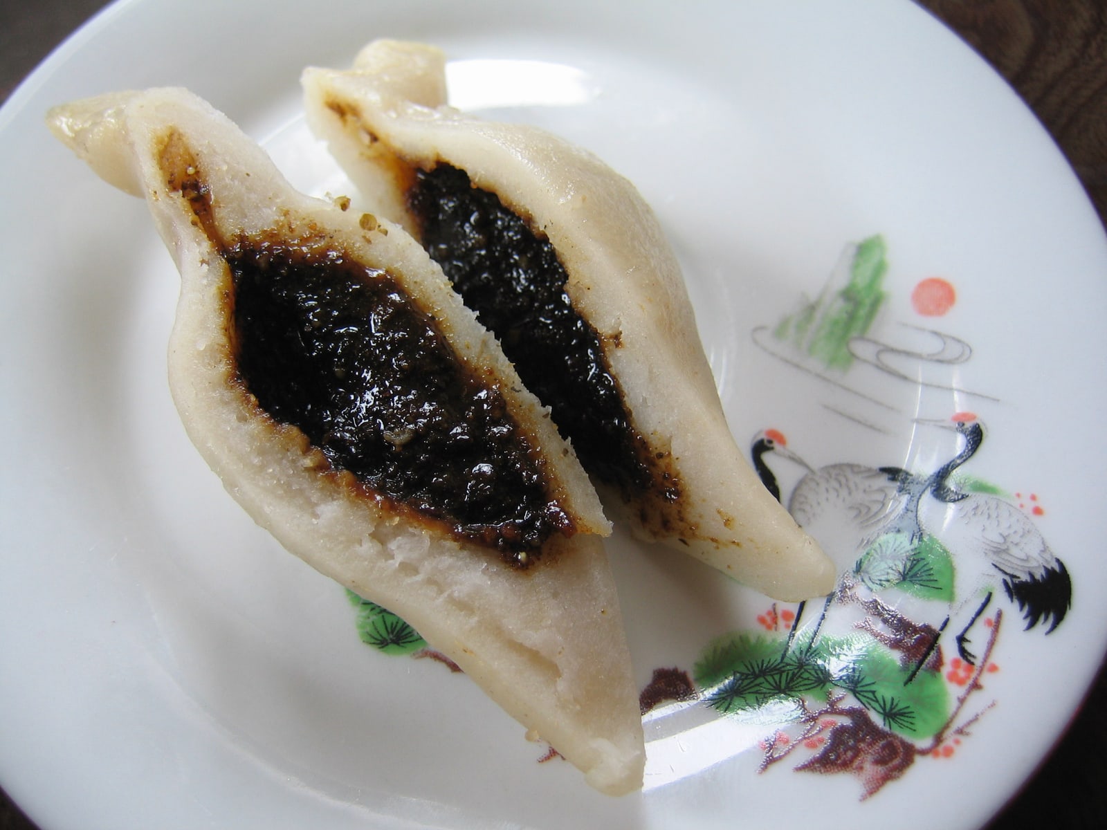 掰开的 yomari 露出深色馅料，其中点缀着芝麻，外面是厚实的白色米粉皮。