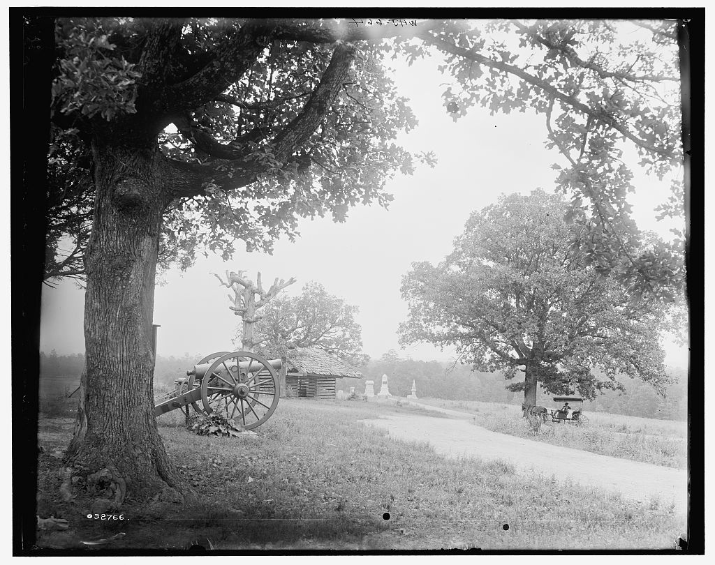 Historical black-and-white photograph of the Snodgrass House grounds at Chickamauga, with a large tree and cannon in the foreground.