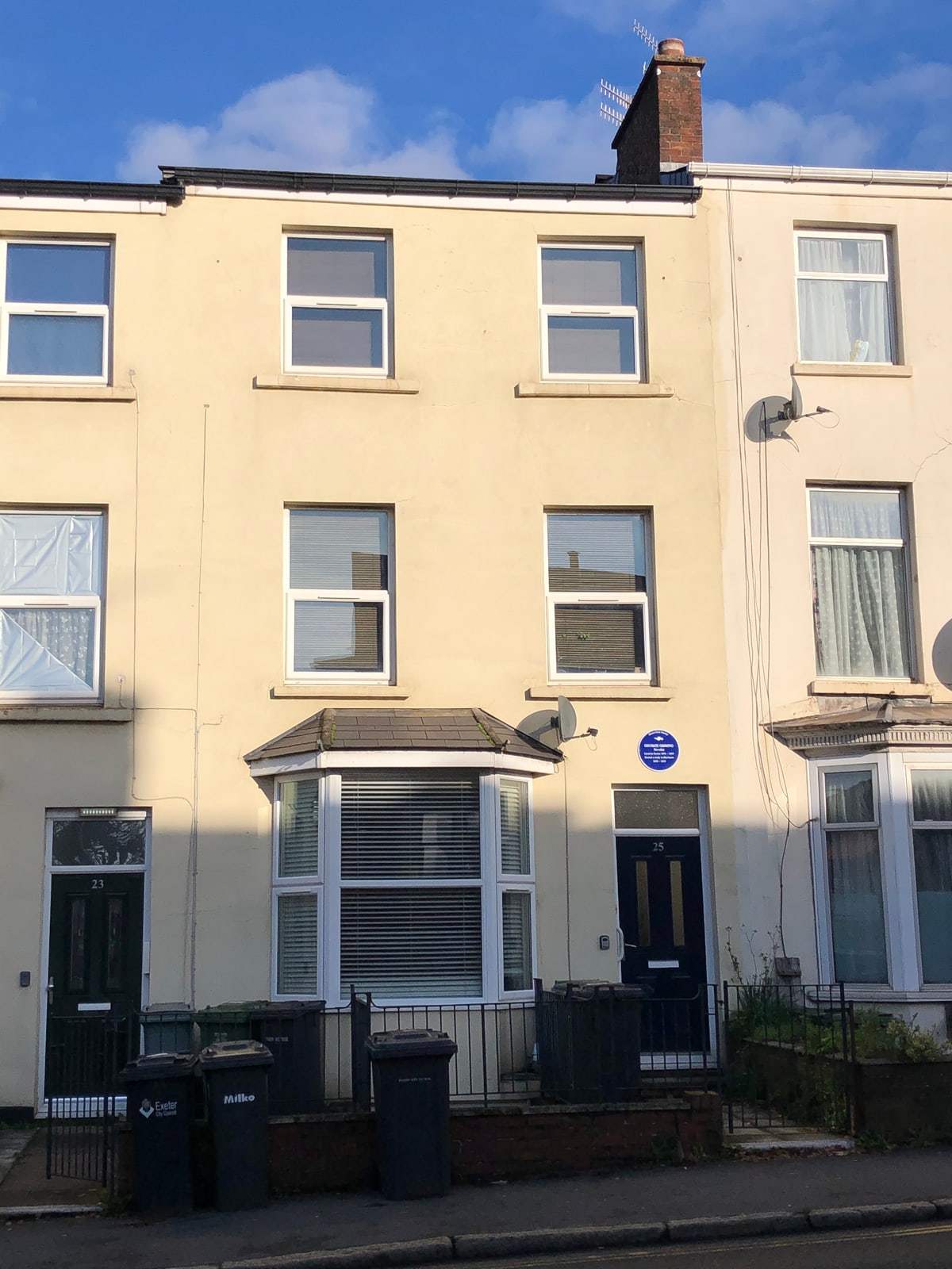 Cream-colored terraced house at 25 Heavitree Road, Exeter, with a blue plaque above the door marking George Gissing's rented study.