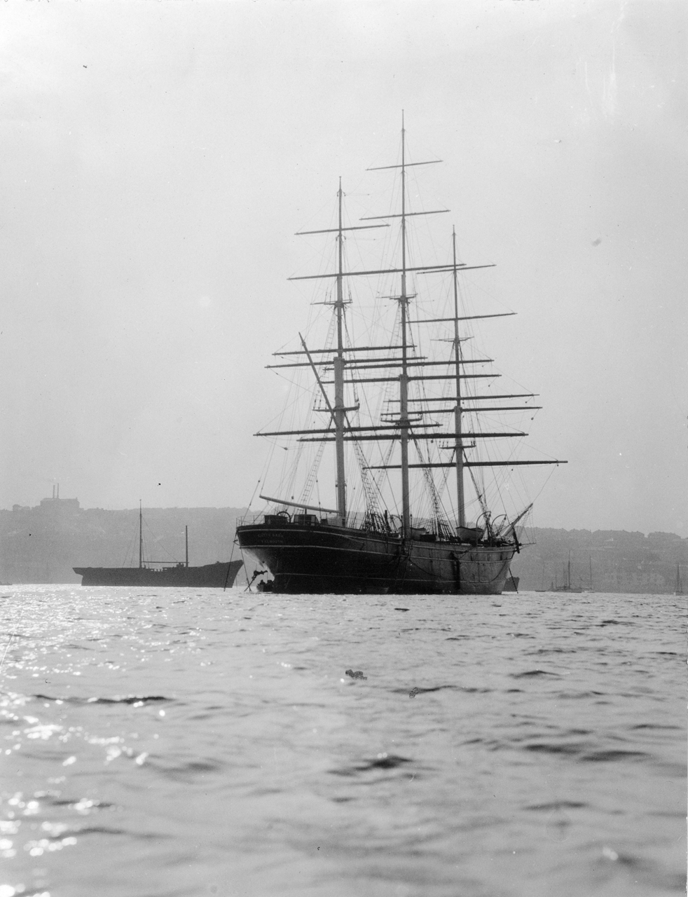 Archival photograph of the sailing ship Cutty Sark at Falmouth, with its tall masts and rigging above the water.