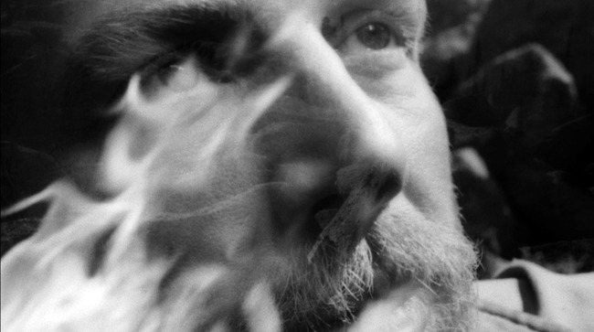 Close-up of Sabinin's face with flames superimposed across the left side of the black-and-white frame.