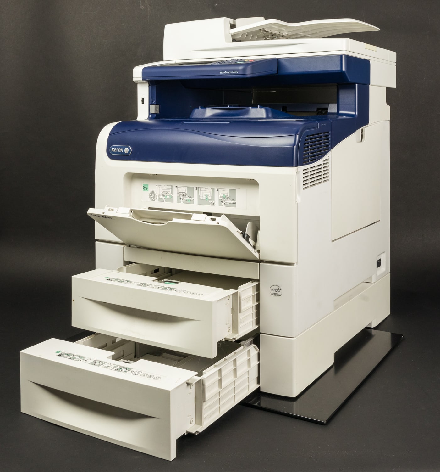 A white-and-blue Xerox WorkCentre multifunction printer with open paper drawers and a recessed output tray.