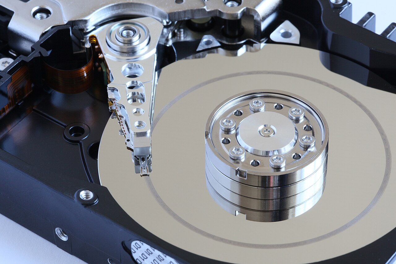 An opened hard drive with concentric scratches across its reflective platter beside the read-write head assembly.