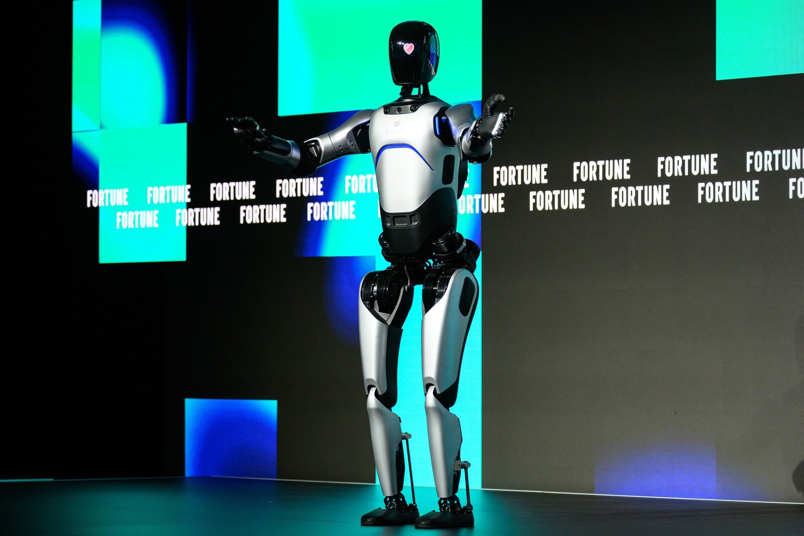 一张真实照片：人形机器人 AGIBOT A2 站在 Fortune 活动舞台上。