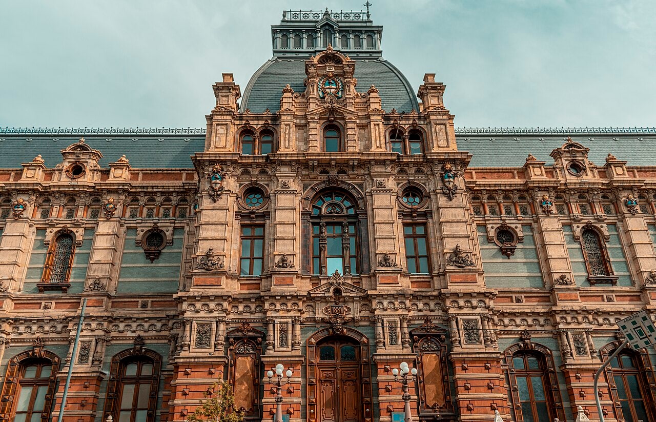 The ornate red and cream ceramic façade of Buenos Aires’s Palacio de Aguas Corrientes, with green slate roofs, sculpted coats of arms and a central arched doorway.