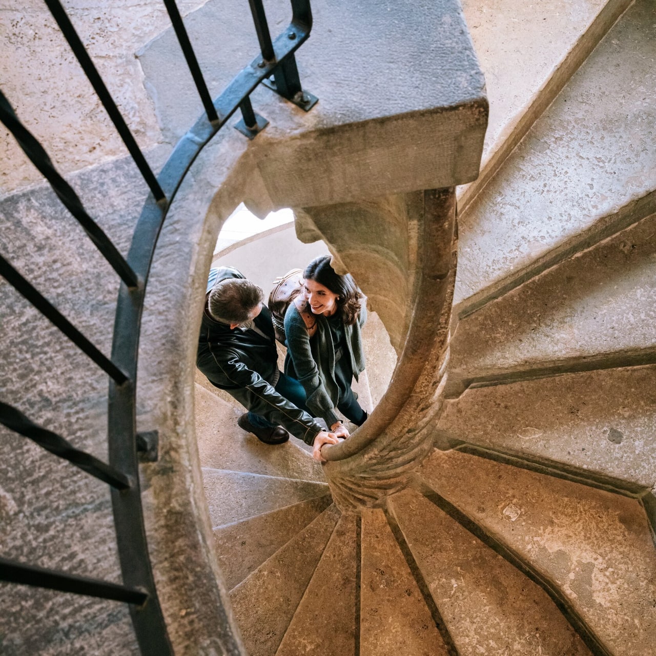 Two visitors on the curving stone flights of the double spiral staircase inside the Grazer Burg.