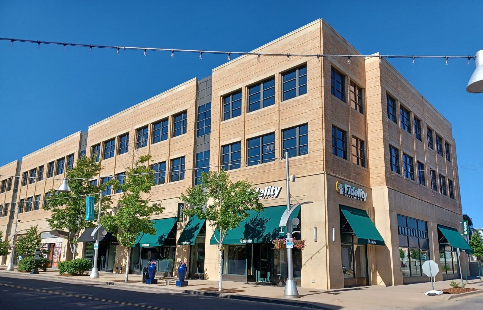 Fidelity Investments signs on a brick and glass storefront beside a sunny sidewalk in Belmar, Lakewood, Colorado.