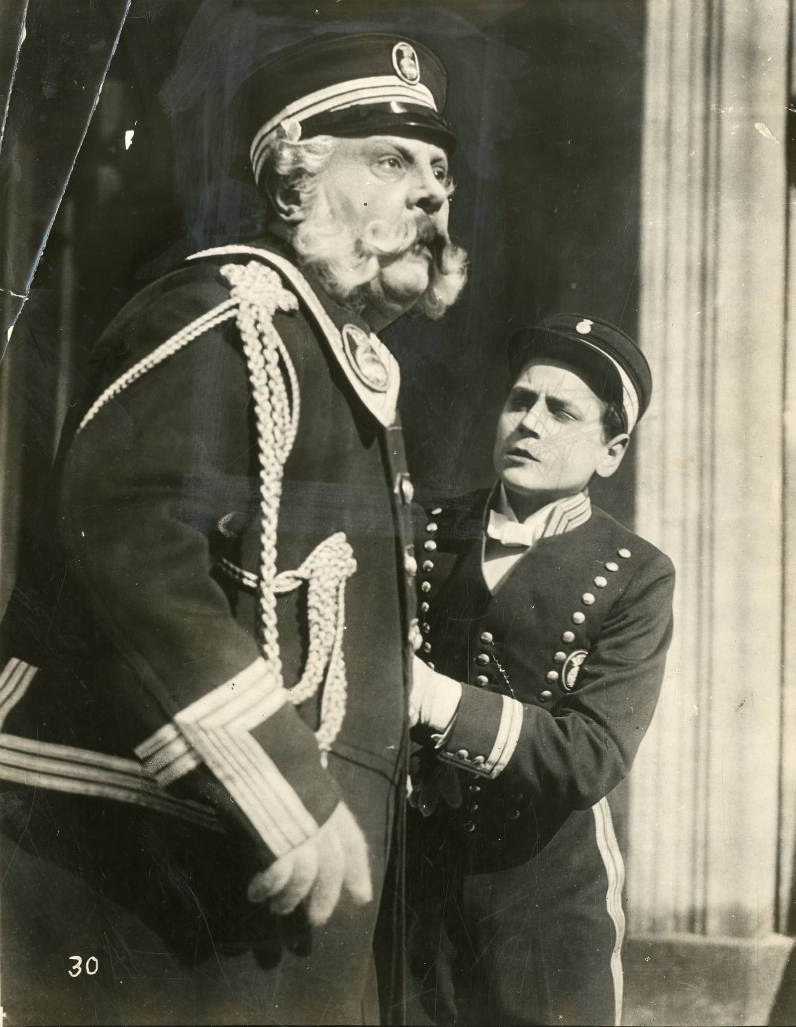 Archival publicity still from The Last Laugh showing Emil Jannings in uniform beside a young boy.